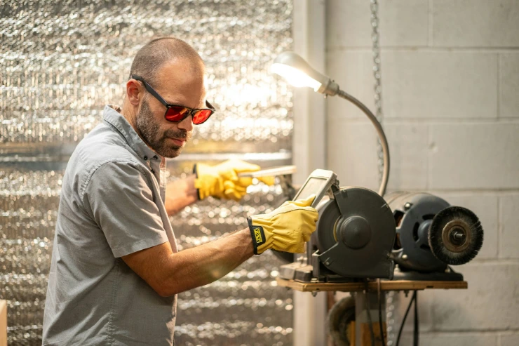 A man in a gray shirt and yellow gloves